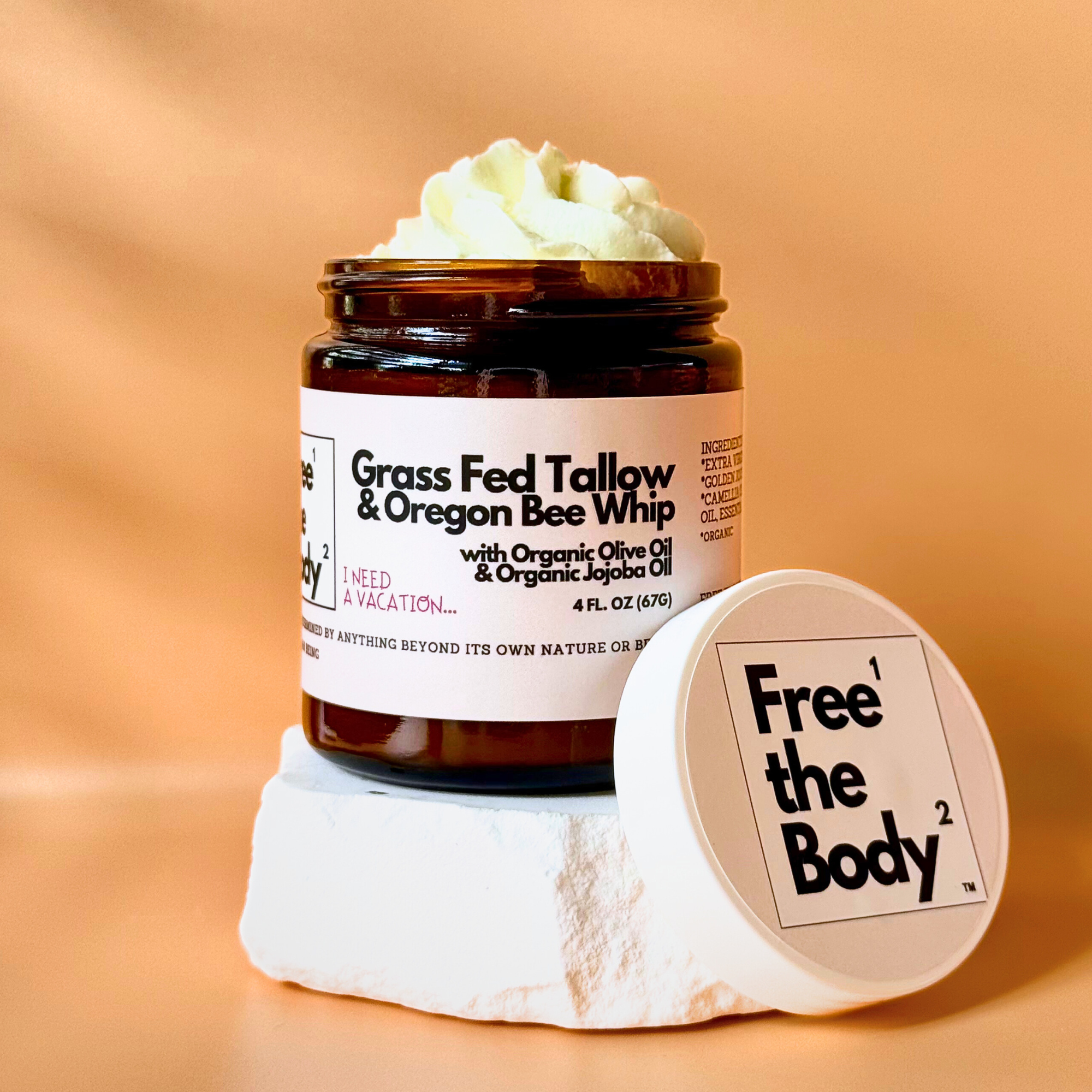 Jar of 'Grass Fed Tallow & Oregon Bee Whip' with a white container labeled 'Free the Body' on an orange background