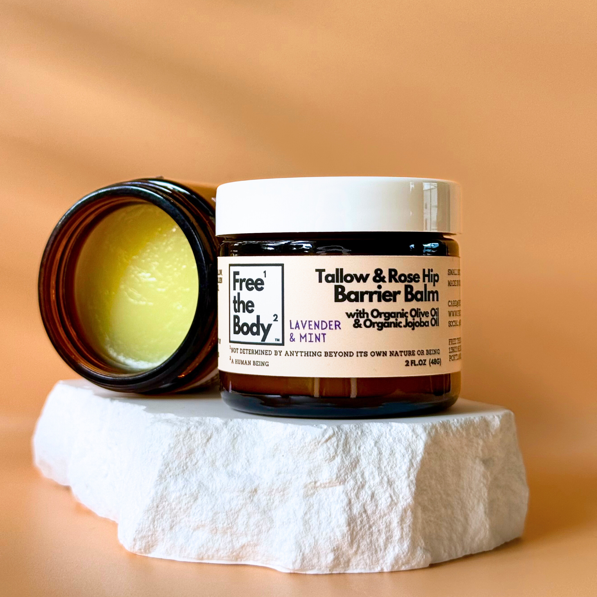 Tallow & Rose Hip Barrier Balm jar with open lid on a stone surface against an orange background